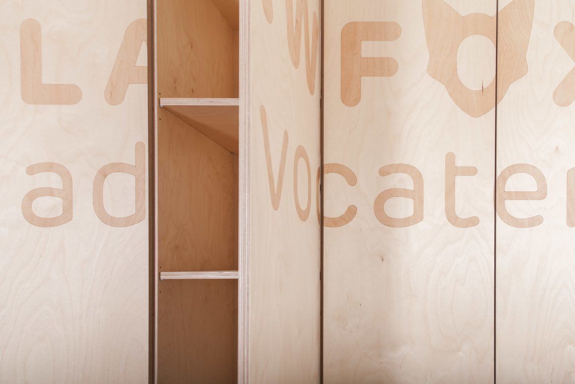 Interieur van houten kantoor met de tekst "La Fox Advocate" en planken.