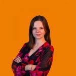 Vrouw met gekruiste armen in bloemenjurk voor oranje achtergrond.
