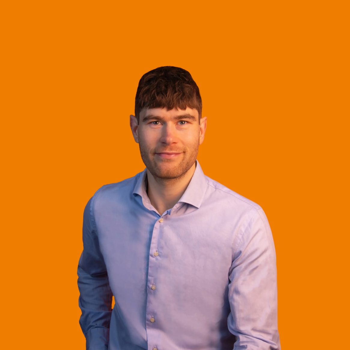 Man in lichtblauw overhemd tegen oranje achtergrond.